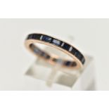 A ROSE METAL FULL ETERNITY RING, set with a full row of square cut deep blue sapphires, channel