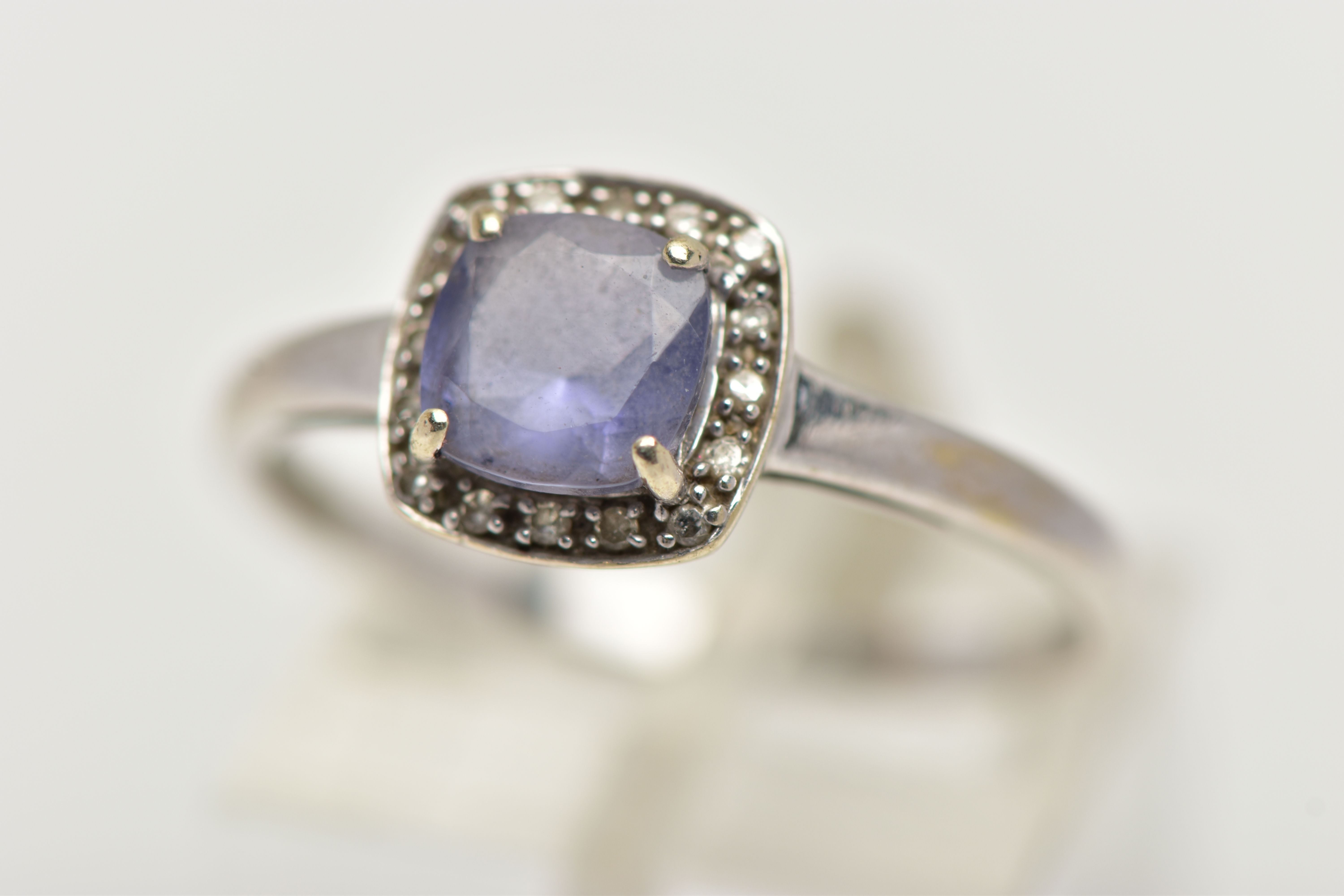 A WHITE METAL IOLITE AND DIAMOND CLUSTER RING, designed with a square cut iolite within a surround