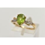 A 9CT GOLD, PERIDOT AND DIAMOND RING, designed with a four claw set, pear cut peridot, flanked