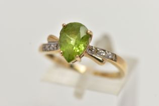 A 9CT GOLD, PERIDOT AND DIAMOND RING, designed with a four claw set, pear cut peridot, flanked