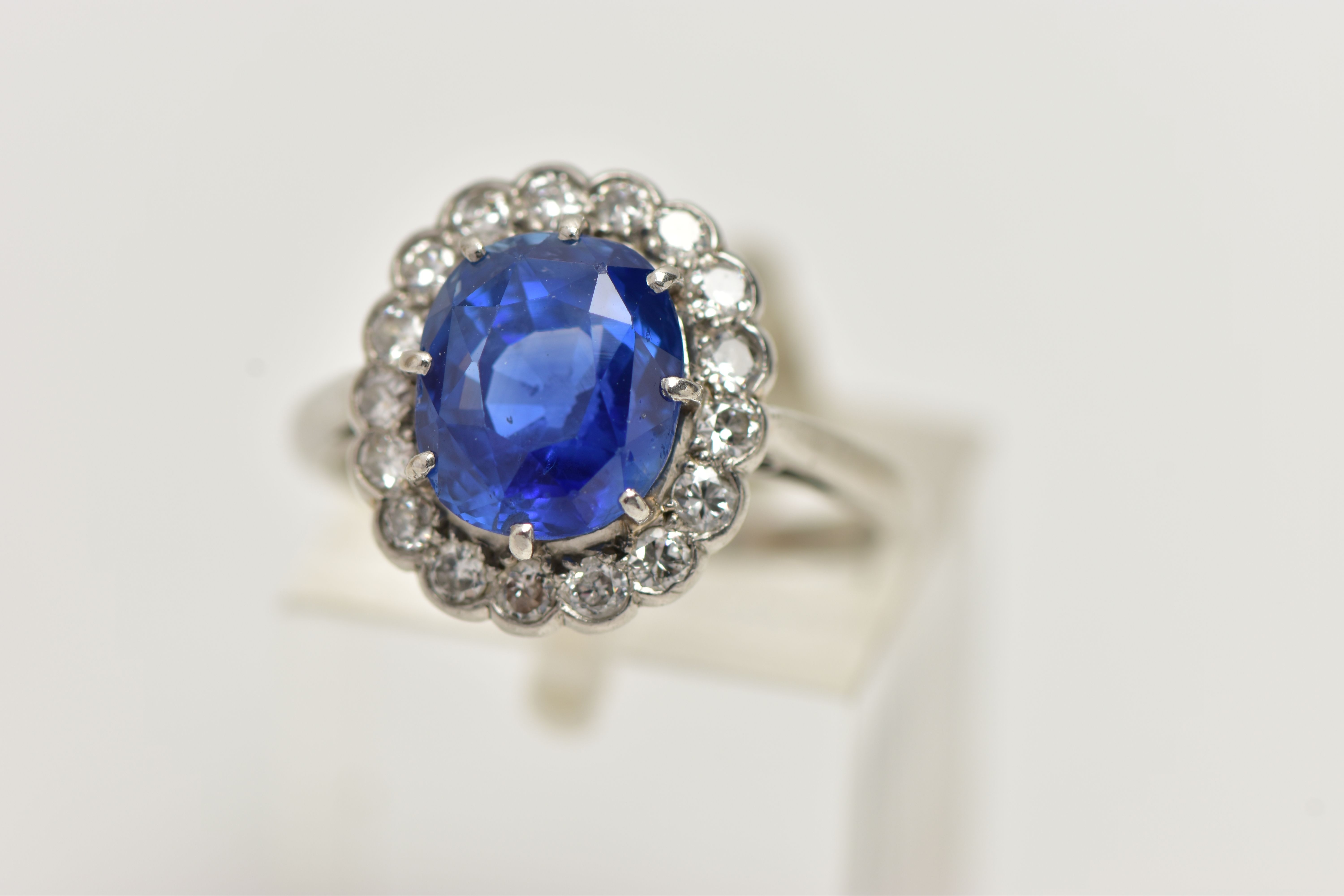 A SAPPHIRE AND DIAMOND CLUSTER RING, set with a mixed cut, cushion sapphire, measuring approximately