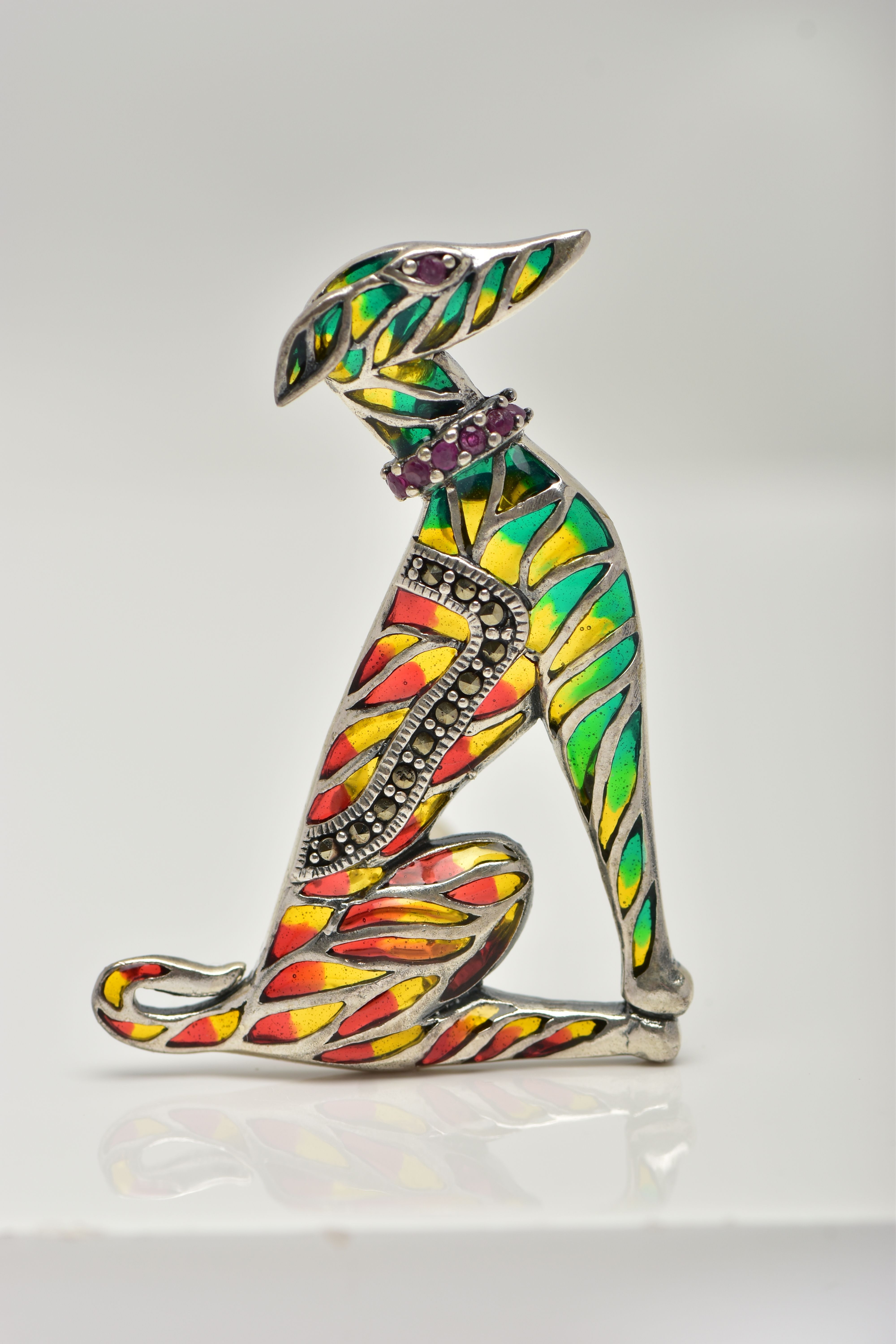 A WHITE METAL PLIQUE A JOUR BROOCH, in the form of a seated dog, decorated with red, green and
