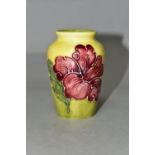 A SMALL MOORCROFT POTTERY HIBISCUS VASE, tube lined with red/purple hibiscus on a graduated yellow