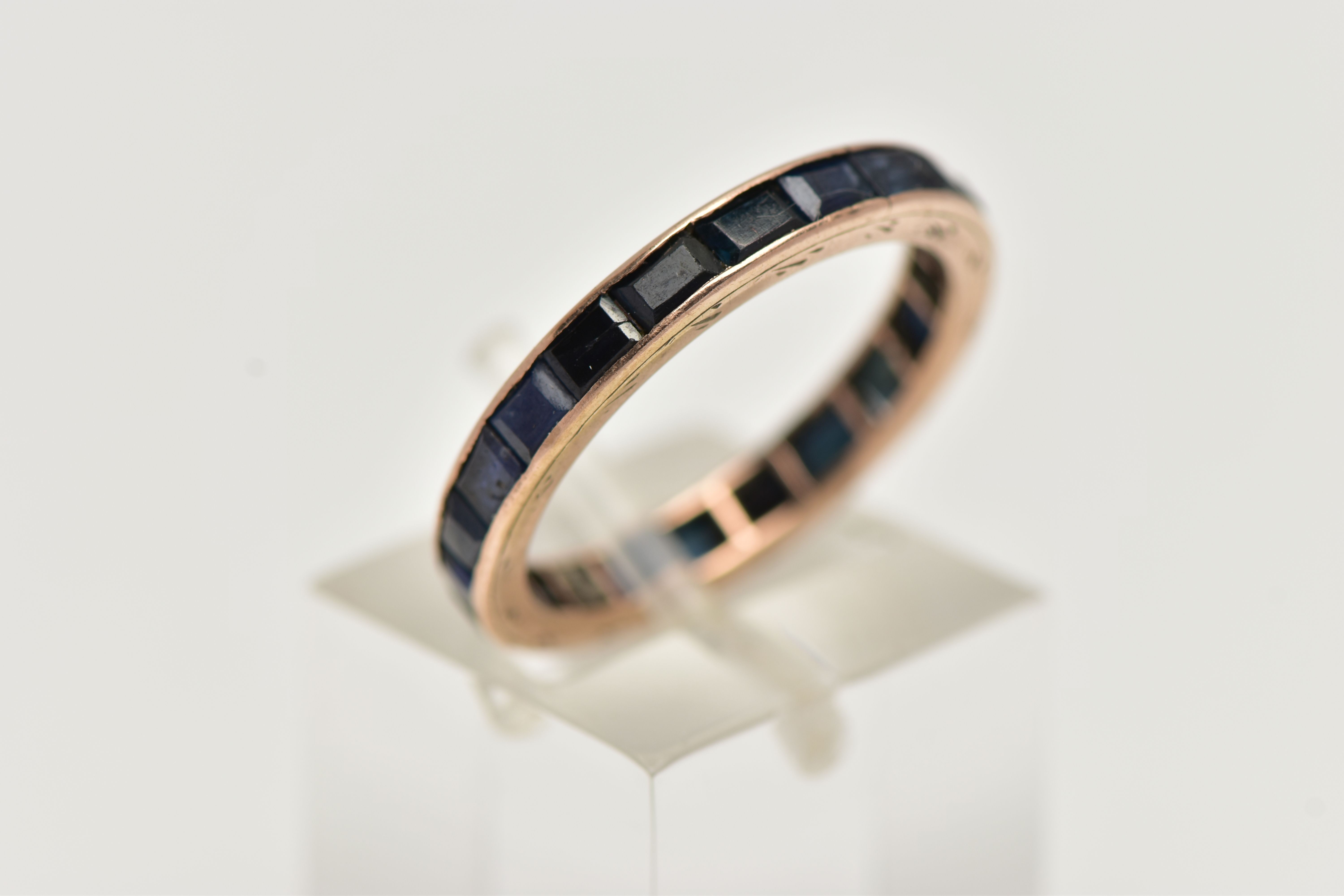 A ROSE METAL FULL ETERNITY RING, set with a full row of square cut deep blue sapphires, channel - Image 4 of 4