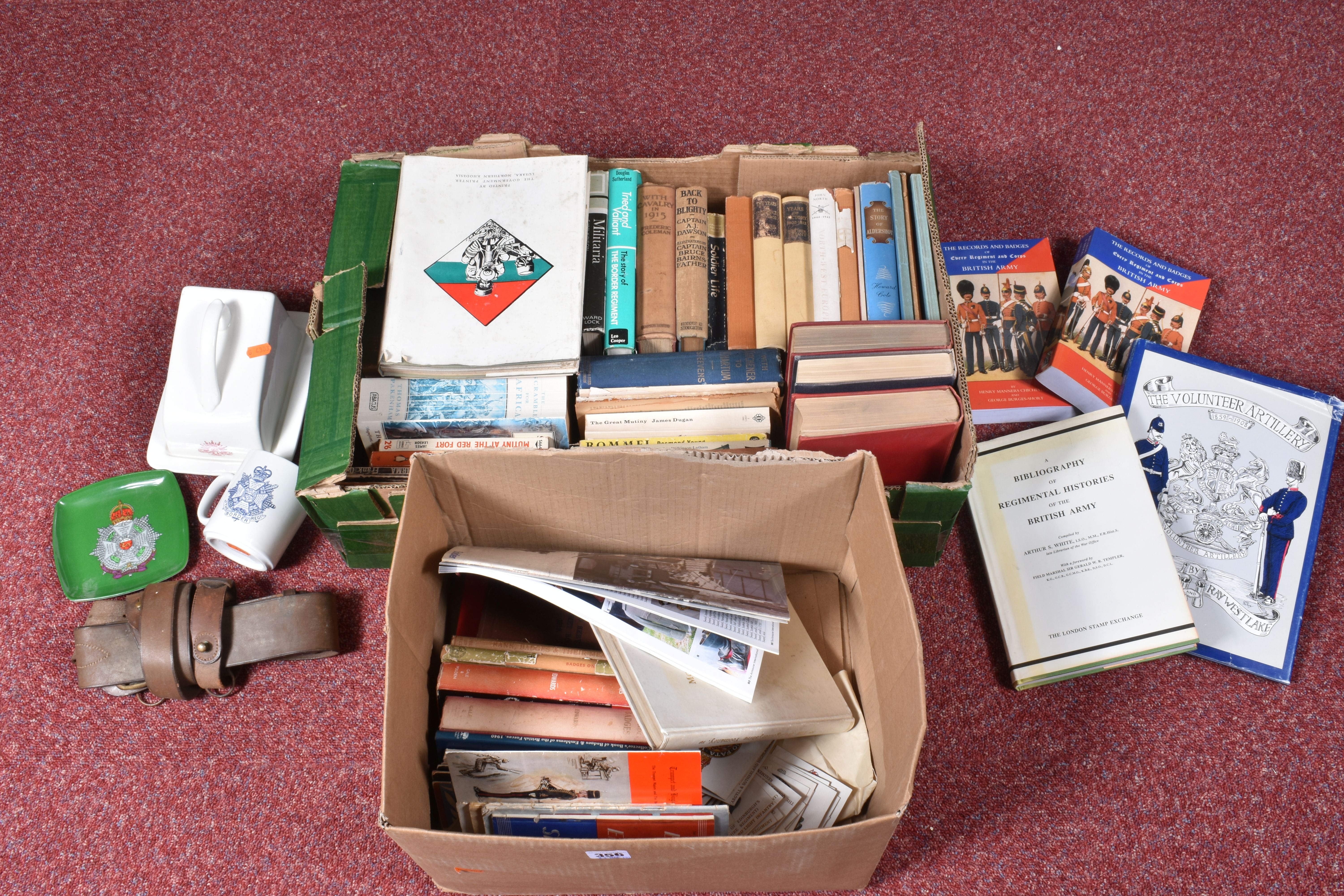 TWO BOXES OF BOOKS AND OTHER MILITARY RELATED ITEMS, to include a border regiment mug, a butter or