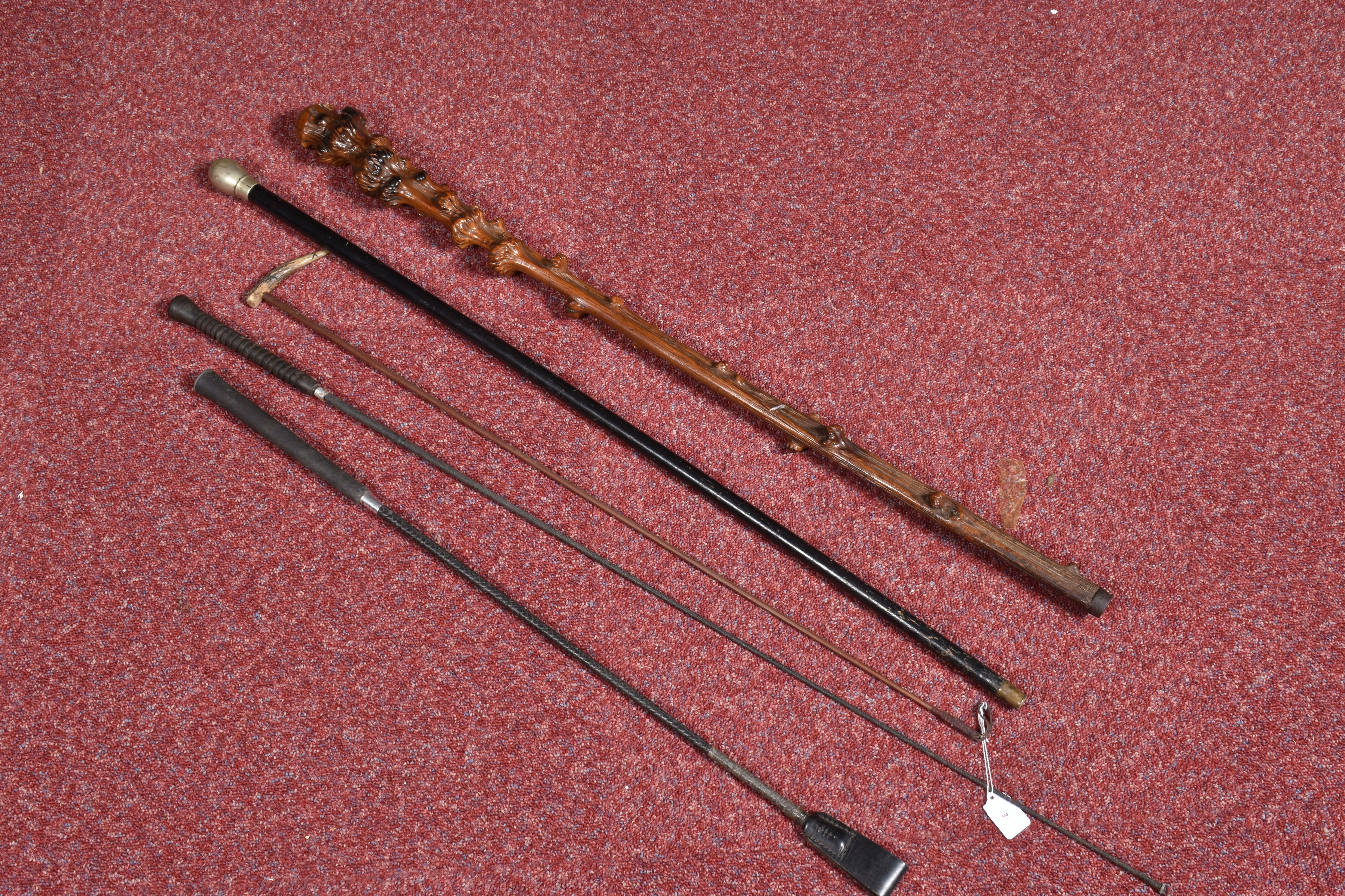 A SELECTION OF WAKLING STICKS AND RIDING CROPS, to include a black walking stick with a dented and