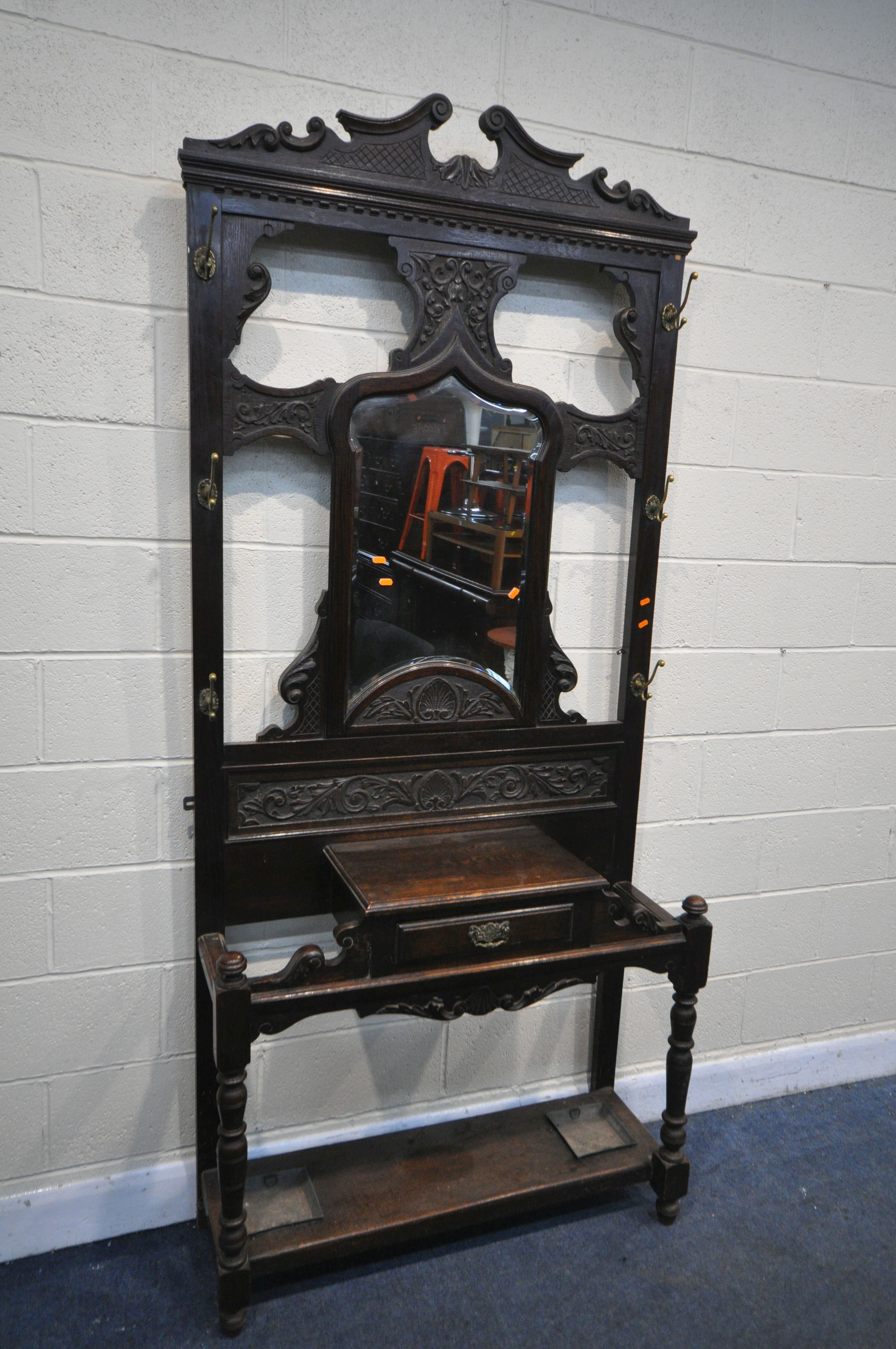 A LATE 19TH CENTURY CARVED OAK HALL STAND, with six brass coat hooks, central shaped bevelled edge