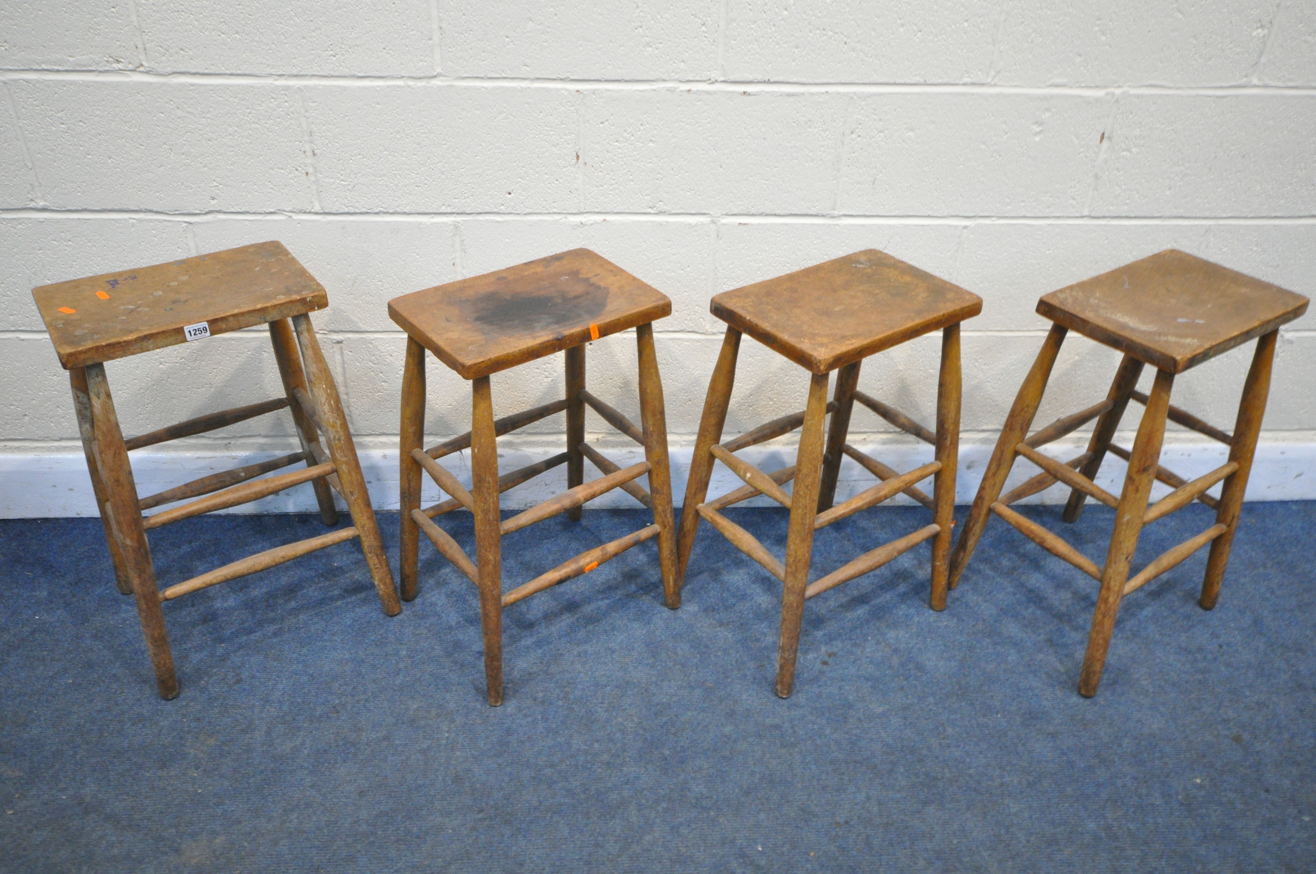 A SET OF FOUR BEECH LABRATORY STOOLS (condition:-distressed finish to all chairs)