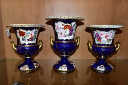 THREE VICTORIAN PORCELAIN TWIN HANDLED URNS, hand painted with panels of flowers on a fish scale