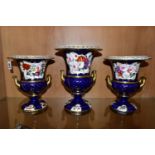 THREE VICTORIAN PORCELAIN TWIN HANDLED URNS, hand painted with panels of flowers on a fish scale