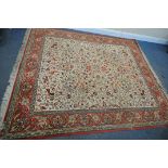 A LARGE 20TH CENTURY CREAM AND RED GROUND RUG, with a repeating floral pattern, and multi-strap