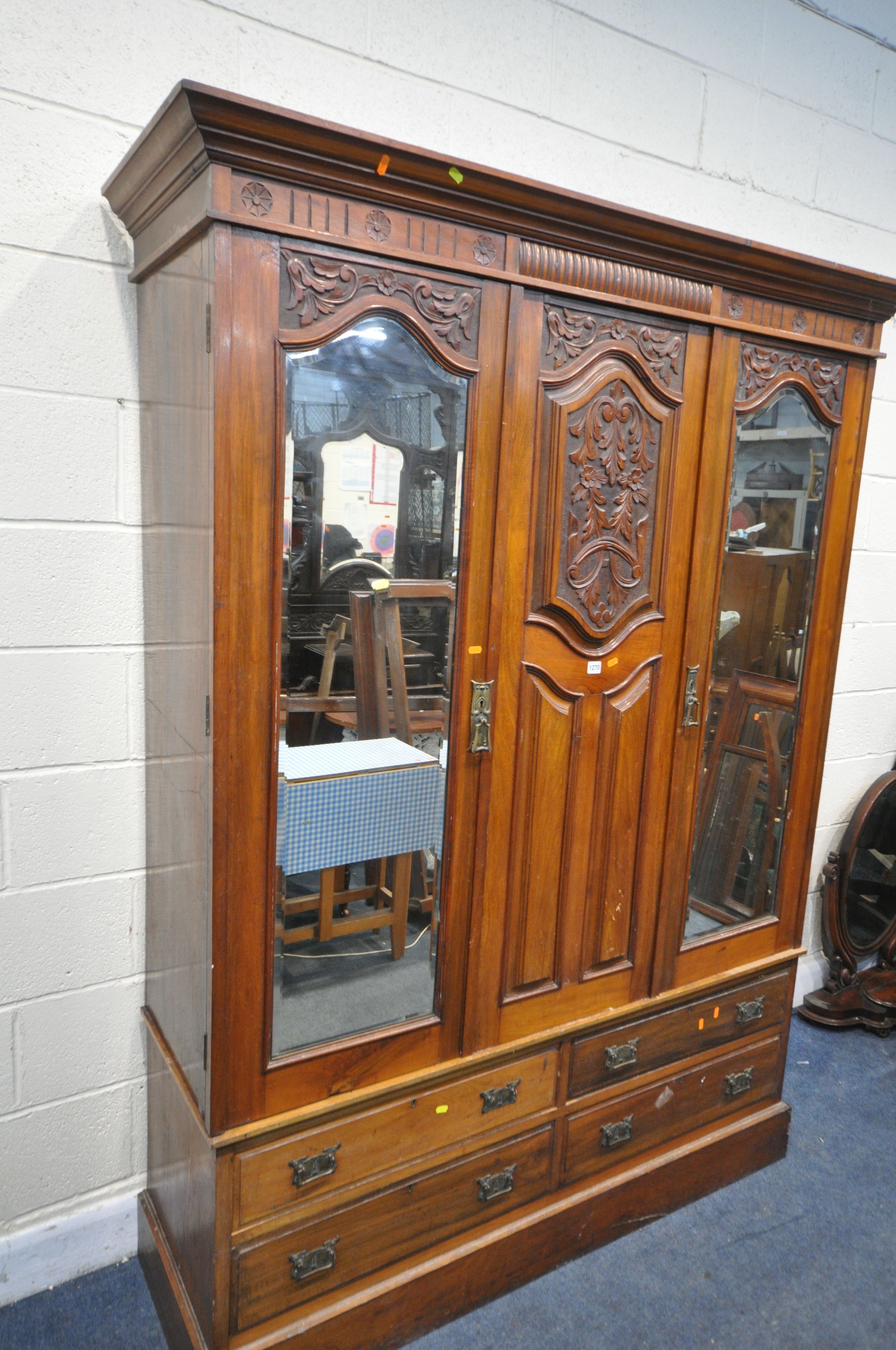 AN EDWARDIAN WALNUT WARDROBE, with two bevelled mirror doors that's flanking a fixed panel, over