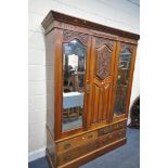 AN EDWARDIAN WALNUT WARDROBE, with two bevelled mirror doors that's flanking a fixed panel, over