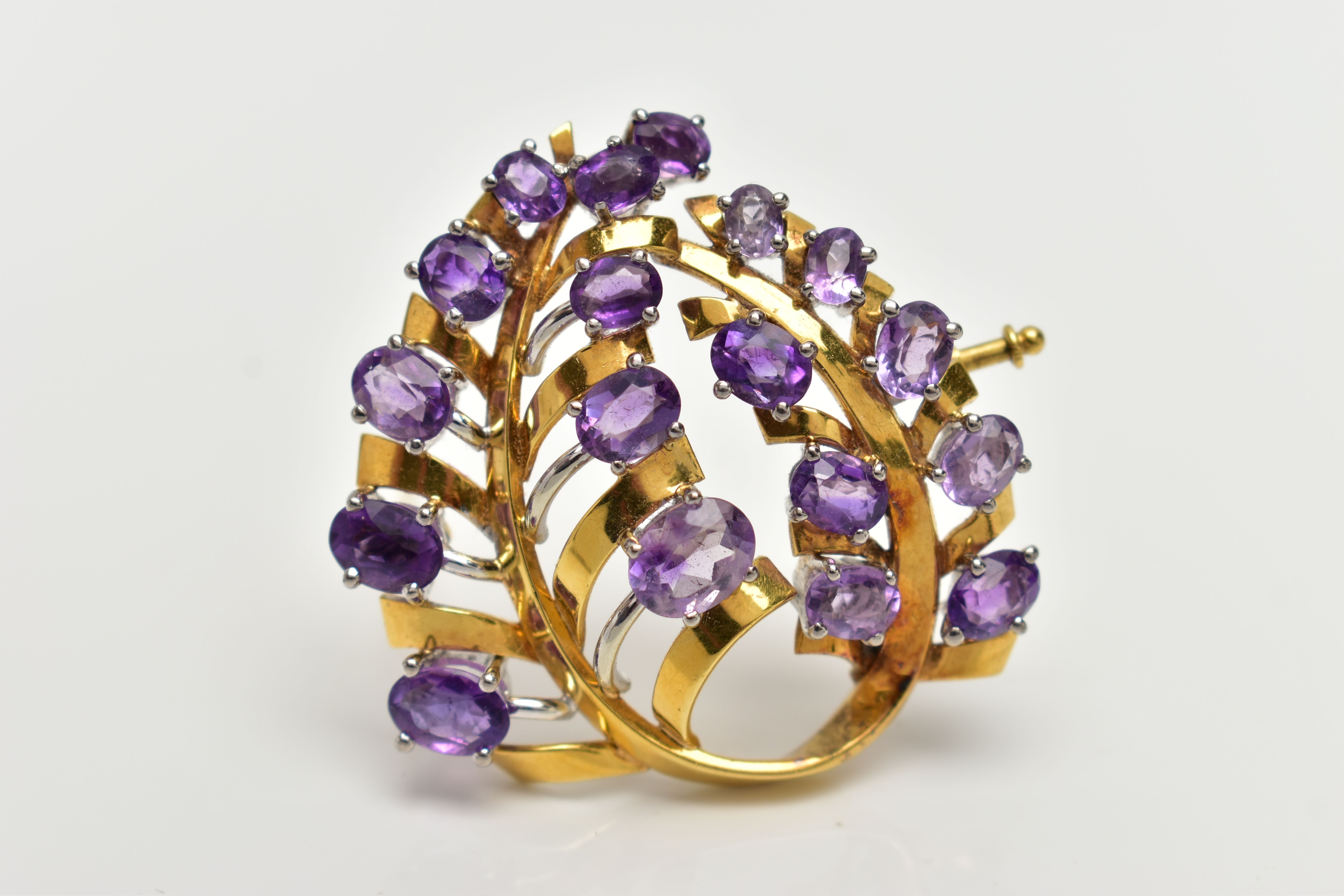 A YELLOW METAL AMETHYST 'LOTOS' SPRAY BROOCH, foliage spray design set with eighteen oval cut