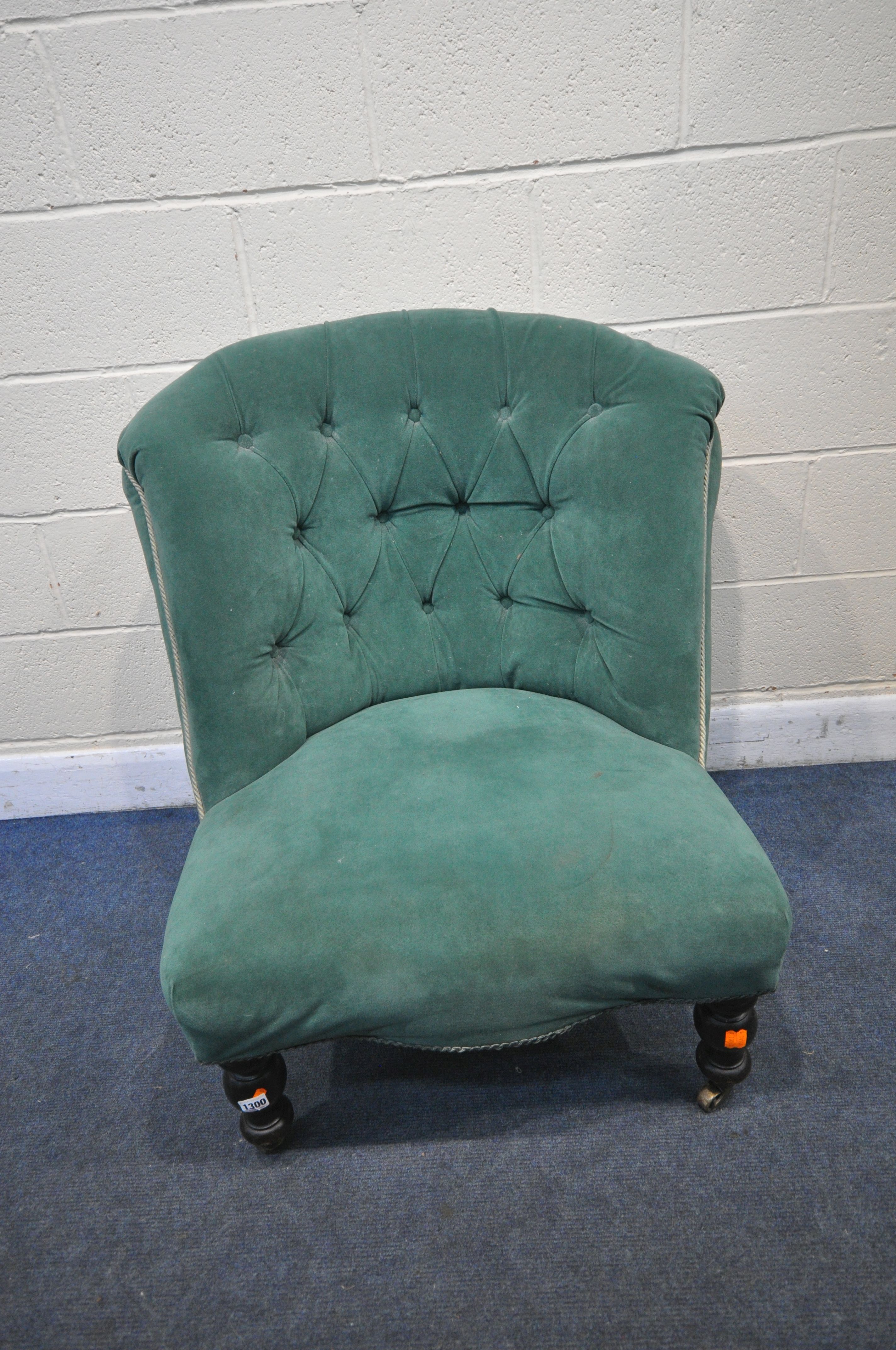 A VICTORIAN BEDROOM CHAIR, reupholstered in green buttoned fabric, on turned front legs and brass