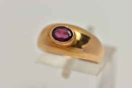 A YELLOW METAL GARNET SET RING, set with an oval cut garnet in a raised collet setting, to a