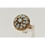 A YELLOW METAL OPAL RING, tiered ring set with nineteen opal cabochons, to the openwork scroll