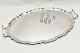 AN EPNS TWIN HANDLED TRAY OF WAVY OVAL FORM AND THREE PLATED KNIFE RESTS, the tray with scrolled