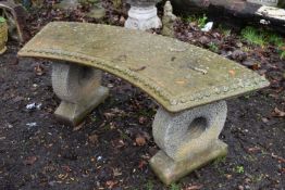 A WEATHERED COMPOSITE CURVED GARDEN BENCH, on circular shaped supports, length 122cm x depth 42cm