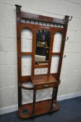 AN EDWARDIAN WALNUT HALL STAND, with six brass hooks, flanking a central mirror, tiles, and