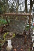 A WEATHERED TEAK GARDEN SWING BENCH, with canopy width 220cm x depth 114cm x height 169cm (no canopy