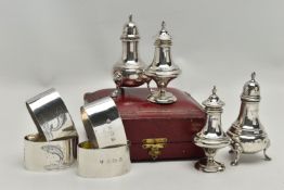 A CASED PAIR OF EDWARDIAN SILVER PEPPERETTES, FOUR OVAL SILVER NAPKIN RINGS AND A MATCHED PAIR OF