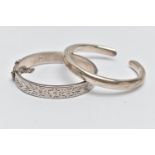 A SILVER HINGED BANGLE AND WHITE METAL CUFF BANGLE, a silver bangle with an etched floral design,