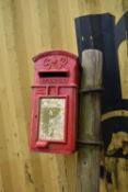 A GEORGE VI CAST IRON HANGING POST BOX with single door and lock (no key), painted in pillbox red,