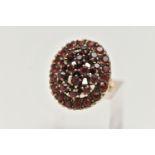 A 9CT GOLD GARNET DRESS RING, of a large oval openwork outline, set with circular cut garnets,
