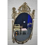 A GILT METAL WALL MIRROR, with a scrolled frame and an oval plate, 51cm x 94cm