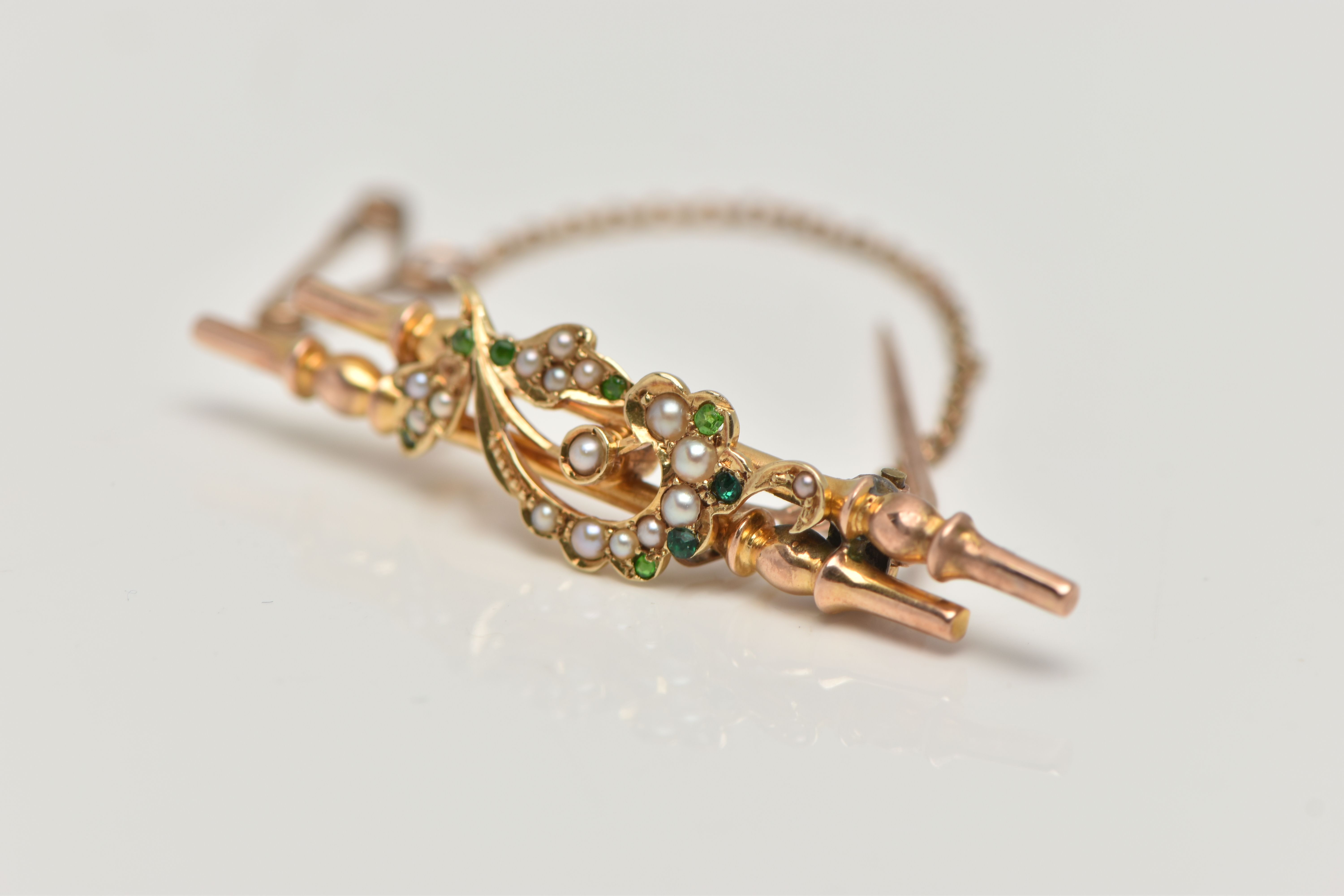 A YELLOW METAL BROOCH, double bar brooch with floral detailing, set with green stones assessed as - Image 2 of 4