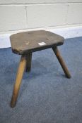 AN ANTIQUE ELM MILKING STOOL (condition:-replacement front two legs)