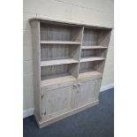 A MODERN LIMED PINE OPEN BOOKCASE, with two shelves within two division over double cupboard doors