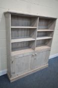 A MODERN LIMED PINE OPEN BOOKCASE, with two shelves within two division over double cupboard doors