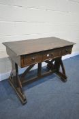 AN ARTS AND CRAFTS OAK TRESTLE SIDE TABLE, with three drawers, on a shaped base united by a shaped