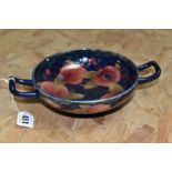 A WILLIAM MOORCROFT TWIN HANDLED FOOTED BOWL DECORATED WITH POMEGRANATE PATTERN ON A DARK BLUE