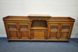 A LONG EARLY 20TH CENTURY OAK BOOKCASE, the double fielded and carved panel doors, below a