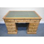 A PINE PEDASTAL DESK, with a green leather and gilt tooled writing surface and nine drawers, width x