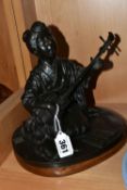 A JAPANESE BRONZE OF A GEISHA KNEELING AND PLAYING A SHAMISEN, cast as singing and with book of