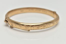 A 9CT GOLD HINGED BANGLE, floral pattern to the front, fitted with an integrated push piece clasp