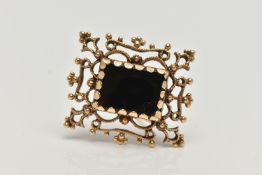 A YELLOW METAL ONYX BROOCH PENDANT, a rectangular cut onyx set within an open work and beaded design