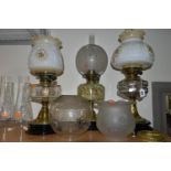 THREE OIL LAMPS AND A SELECTION OF SHADES, the oil lamps all having glass reservoirs - one with