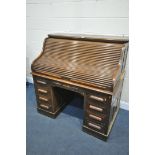 AN EARLY 20TH CENTURY OAK ROLL TOP DESK, enclosing an arrangement of shelving and two drawers,