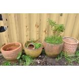 A SELECTION OF WEATHERED TERRACOTTA POTS comprising three circular terracotta pots and a smaller