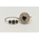 TWO GEM SET RINGS, the first a large oval tiered cluster, set with a central oval cut blue sapphire,