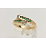 AN EMERALD AND DIAMOND RING, twelve square cut emeralds graduating is size channel set in a yellow