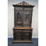 A VICTORIAN CARVED OAK BOOKCASE, depicting masks, foliate detail and fruiting vines throughout,