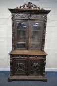 A VICTORIAN CARVED OAK BOOKCASE, depicting masks, foliate detail and fruiting vines throughout,