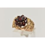 A 9CT GOLD GARNET DRESS RING, yellow gold wide textured and pierced band set with nine circular