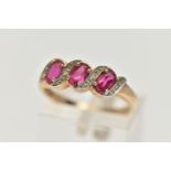 A 9CT GOLD GEM SET RING, three oval cut synthetic rubies accented with four round brilliant cut